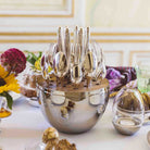 Christofle Mood silver-plated egg-shaped flatware case with 6 table knives, 6 table forks, 6 table spoons, and 6 teaspoons set on a table