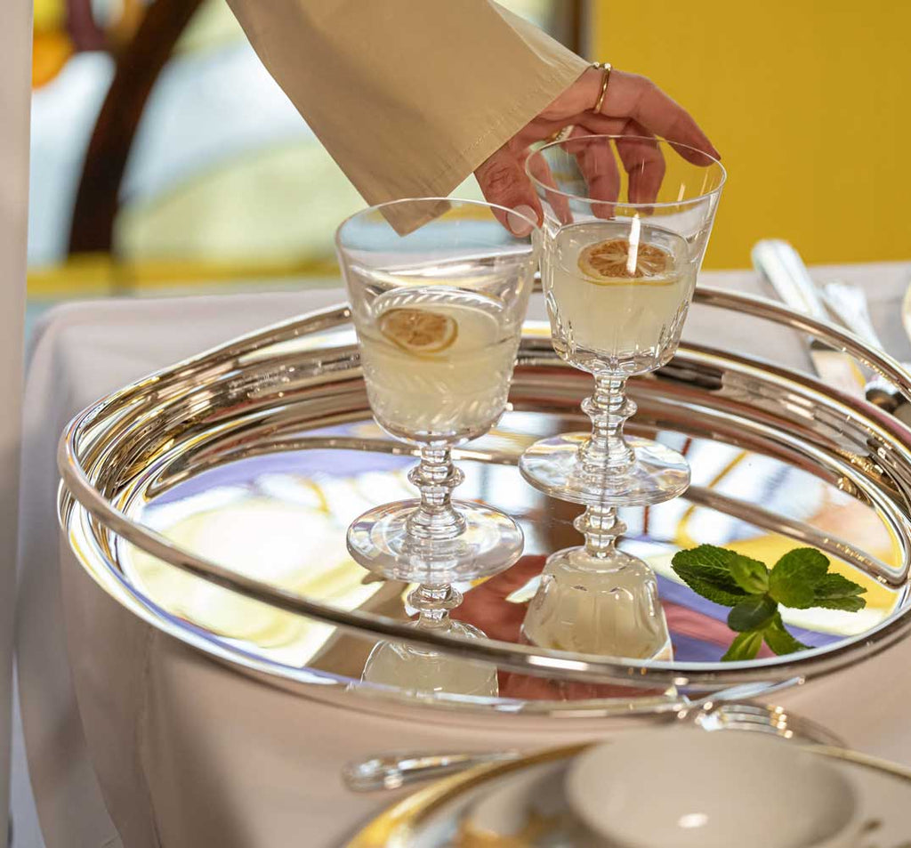 two glasses of drink served on christofle vertigo silver-plated round serving tray 
